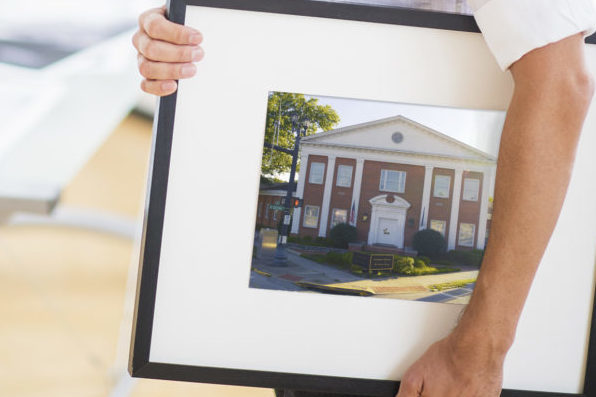 Portrait of man holding photo of IH building